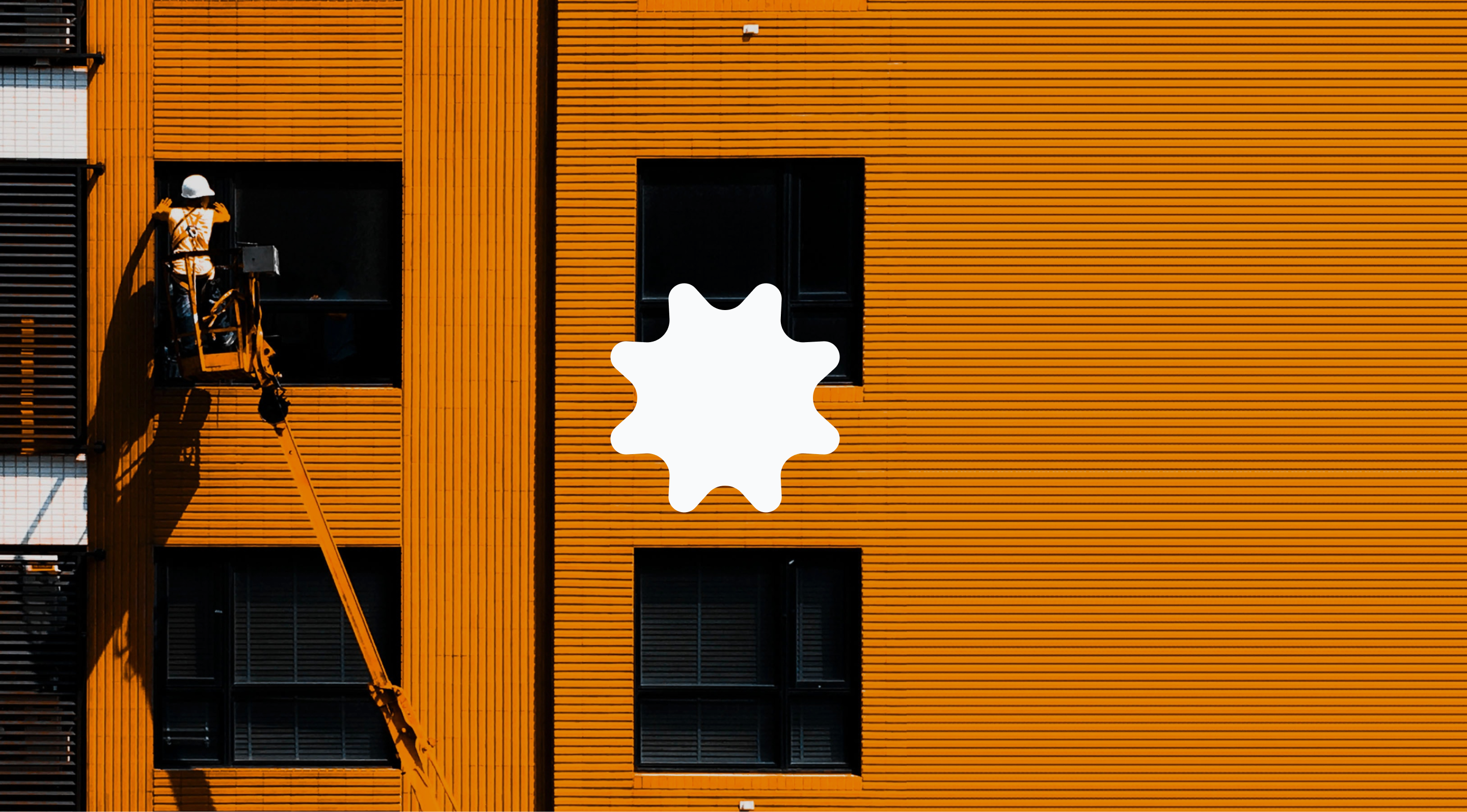 Orange building facade with the maintenance worker on an arial work platform